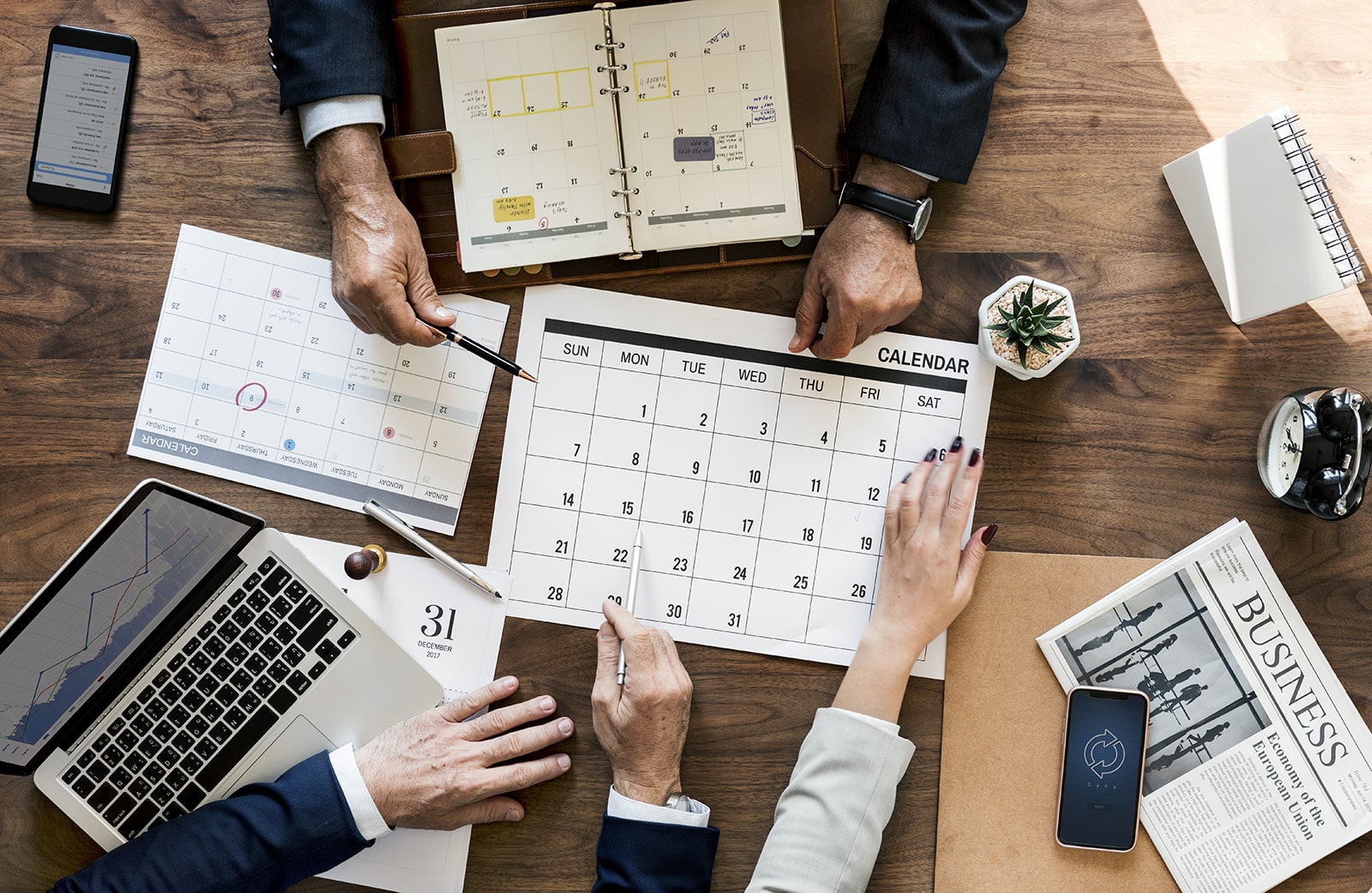 Photo of people scheduling a meeting using a paper calendar.
